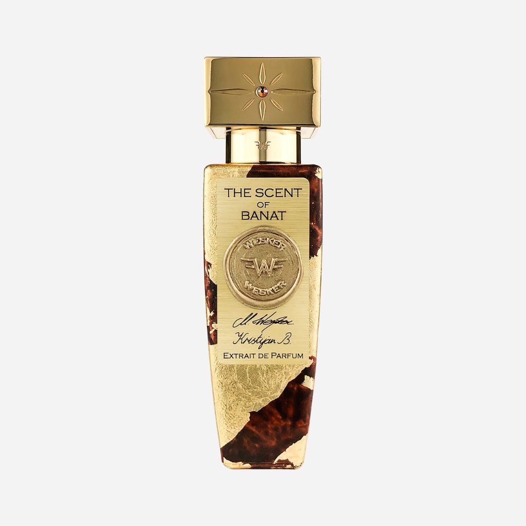 The Scent of Banat Eau de Parfum by Wesker features a gold and brown bottle with ornate detailing, a gold cap adorned with a red gem, embossed front designs, and is crafted with natural ingredients— inspired by Western Banat.