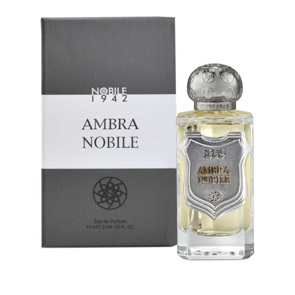 A bottle of AMBRA NOBILE Eau de Parfum by Nobile 1942 stands next to its gray box, featuring a silver shield and cap, gold lettering, and pale yellow liquid in a clear bottle from the I Rigati Collection.