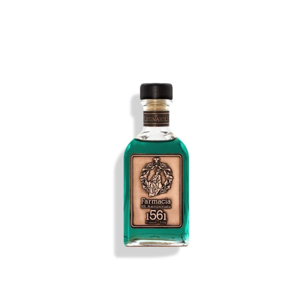 A glass bottle of Legnaioli DIFFUSER by Farmacia SS. Annunziata 1561 holds teal liquid, with a beige label and black reeds suggesting a wood-inspired scent, set against a white background.