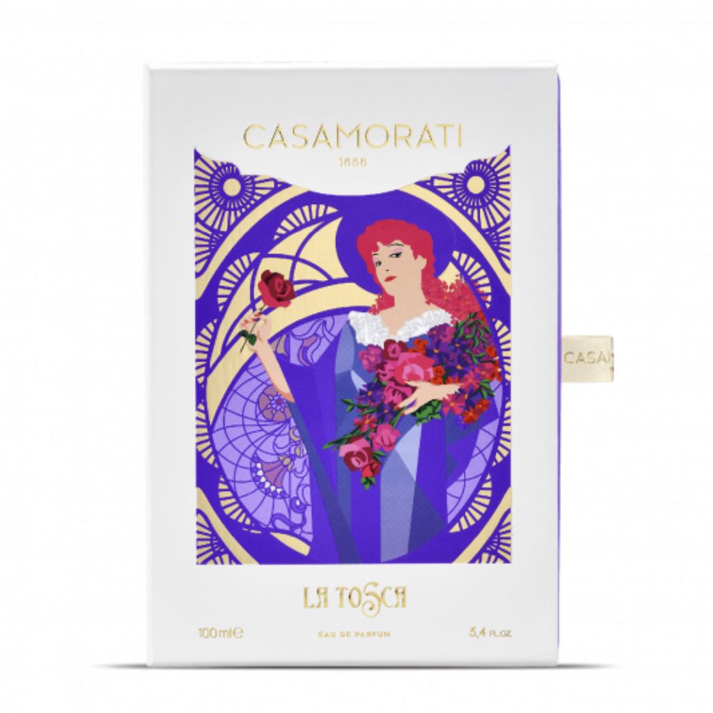 The Casamorati 1888 La Tosca Eau de Parfum by XERJOFF comes in a box featuring an Art Nouveau illustration of a red-haired woman in purple holding roses, reflecting the fragrance’s elegant floral notes.