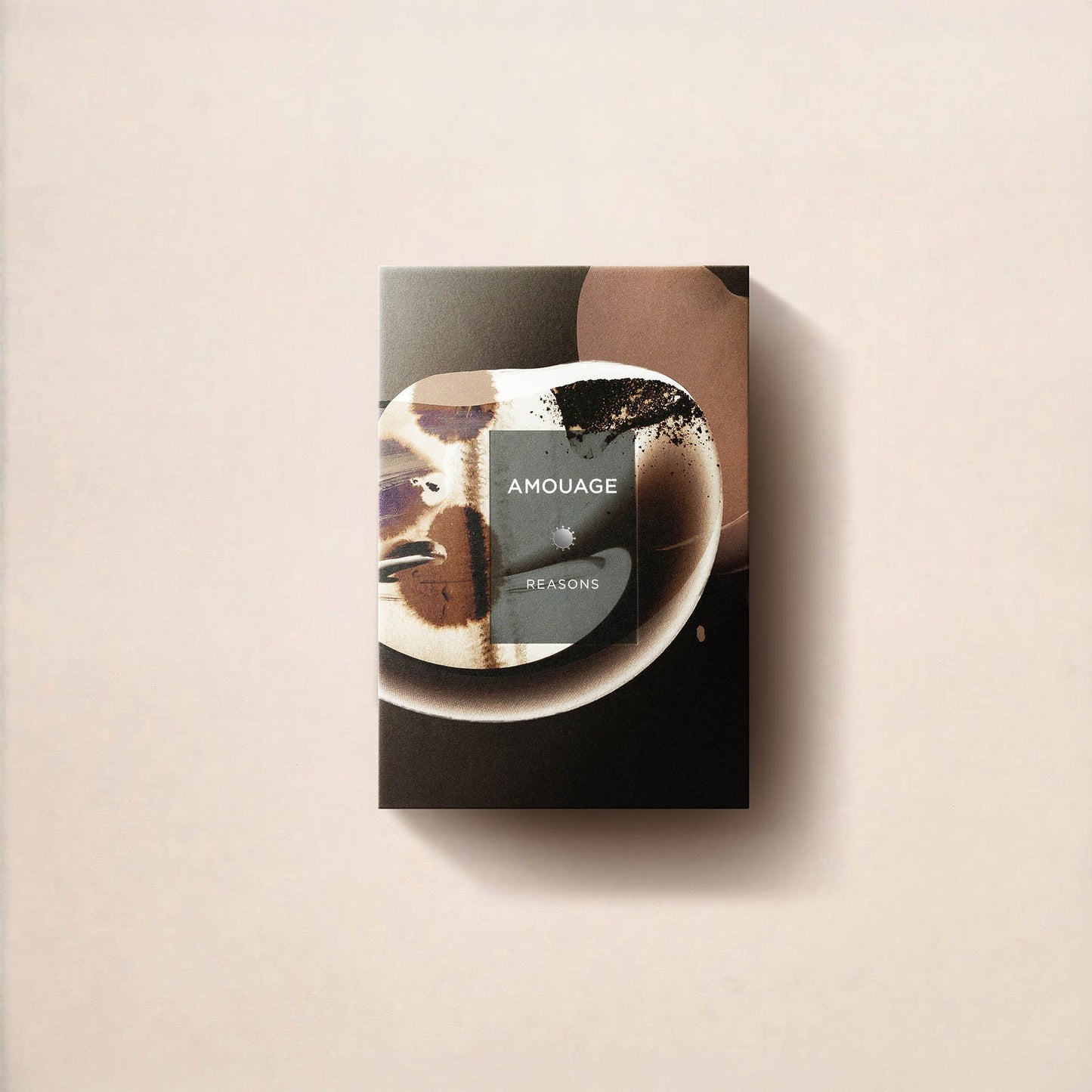 A rectangular box of Fragrapedia Haus Reasons Essence de Parfum, highlighting Amouage Essences and double infusion sandalwood, rests on a light beige surface. Its abstract earthy-toned design casts soft shadows to the right.