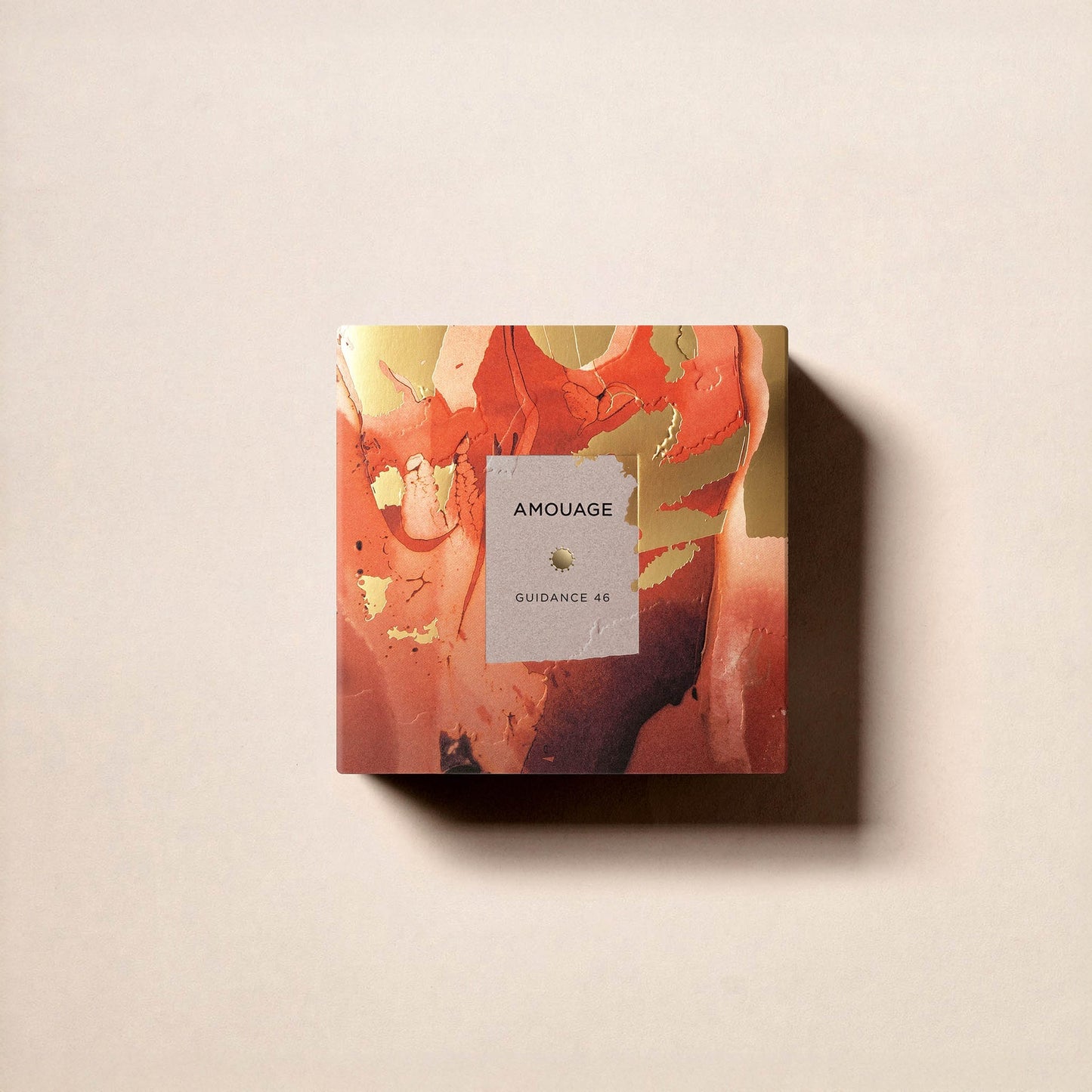 A square Fragrapedia Haus Guidance 46 Extrait de Parfum box with an abstract orange, gold, and brown marbled design rests on a light beige surface, casting a soft shadow. Renowned for its 46% oil concentration.