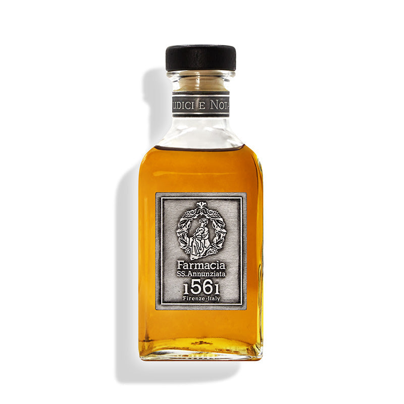 The Giudici e Notai DIFFUSER by Farmacia SS. Annunziata 1561 is a rectangular glass bottle with amber liquid, a black cap, and an ornate silver label. It infuses your space with refined cedar wood notes for an exquisite home fragrance.