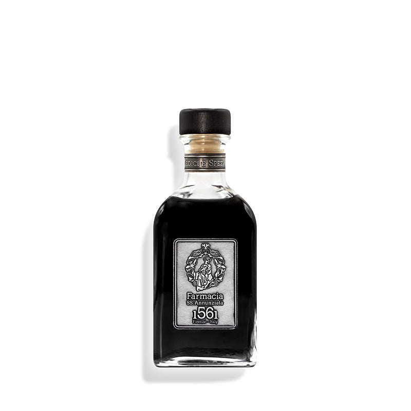A clear glass Medici e Speziali DIFFUSER - Farmacia by Farmacia SS. Annunziata 1561 filled with dark liquid, black cap and sticks, silver label with crest, is set against a white background.
