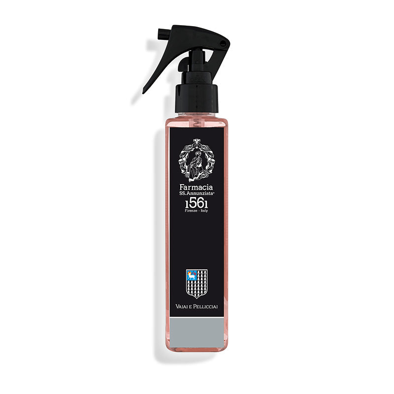 The Vaiai e Pellicciai Room Spray by Farmacia SS. Annunziata 1561 comes in a tall, clear bottle with pink liquid, black label, crest, and shield—ideal for infusing spaces with a fresh floral scent. Made in Italy.