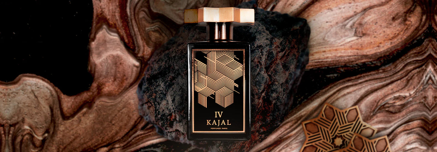 A black and gold bottle of Kajal IV Eau de Parfum by Kajal Perfumes Paris rests on a dark rock, framed by swirling brown, beige, and gold marble—an exotic scent inspired by the wild beauty of the African Savannah.