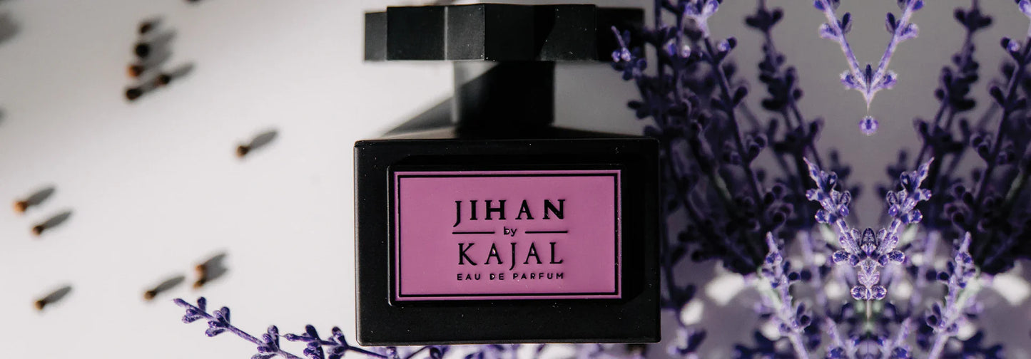 A black “Jihan Eau de Parfum” bottle by Kajal Perfumes Paris with a purple label, surrounded by lavender flowers, saffron, and cloves on a light surface.