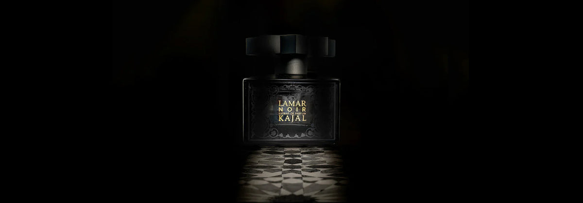 A dark bottle of Lamar Noir Extrait de Parfum by Kajal Perfumes Paris stands on a patterned surface, illuminated against a black background—inviting you into an inner alchemy and transformative journey.