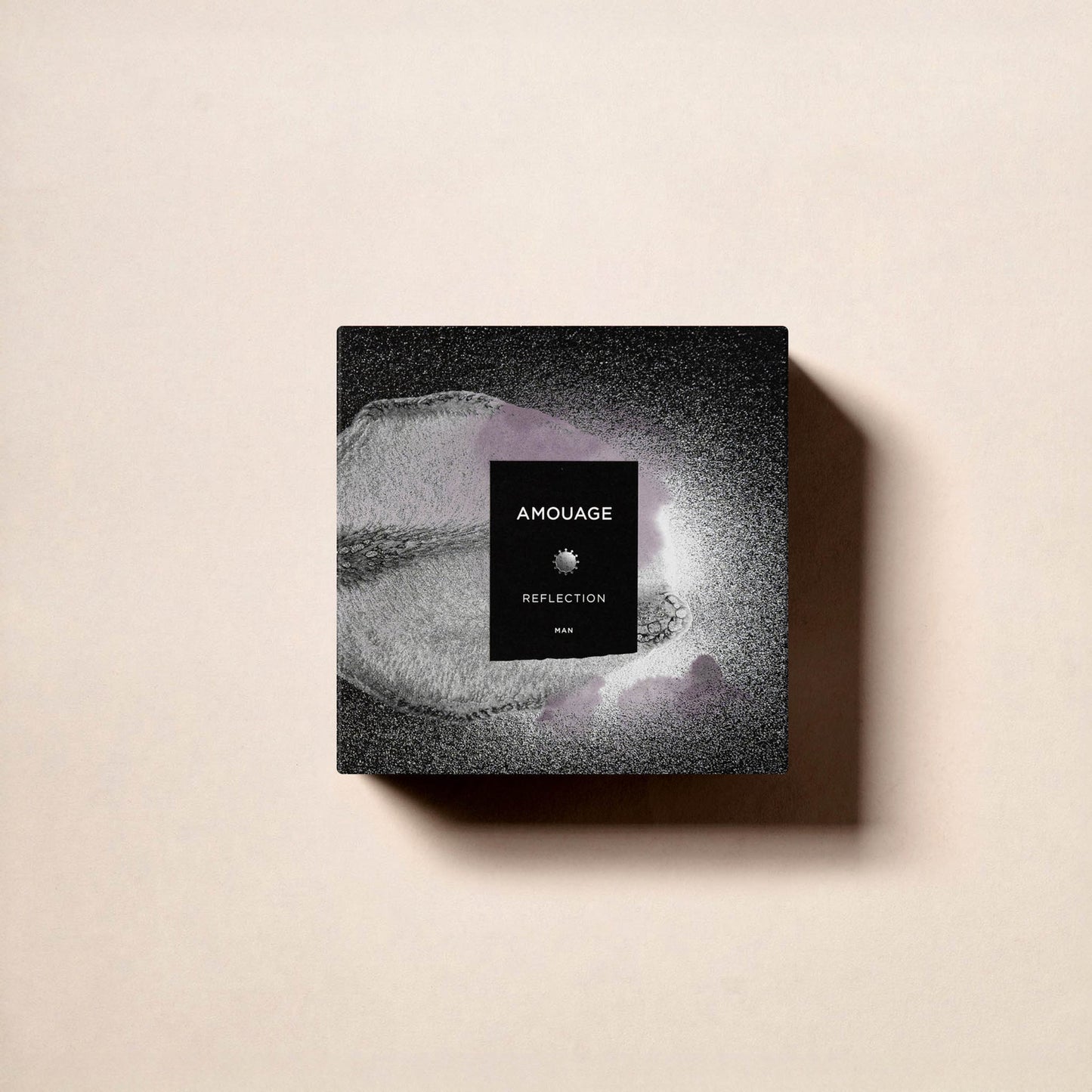 A square black box of Fragrapedia Haus Reflection Man Eau de Parfum rests on a beige surface, its textured design and centered branding reflecting the timeless elegance of this masculine fragrance.