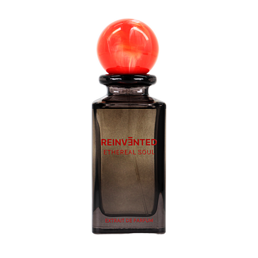A dark glass perfume bottle with a bright red spherical cap bears the REINVĒNTED label reading "ETHEREAL SOUL Extrait de Parfum – REINVENTED" in bold red, suggesting a celestial, fruity oriental fragrance.