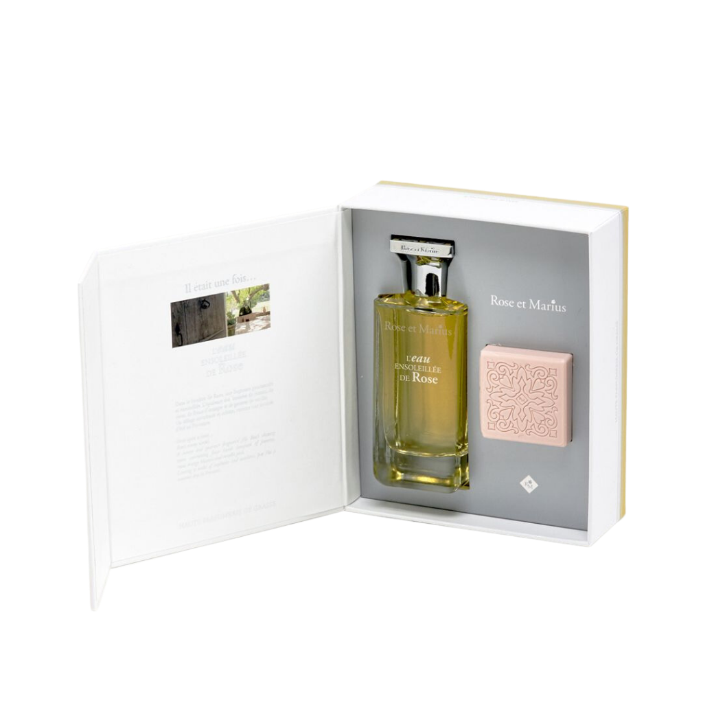 The Rose Et Marius GIFT SET BASKING IN THE SUN WITH MARIUS features a glass Eau Centifolia Rose perfume bottle and a pink, patterned soap, beautifully presented in an open box with printed text inside the lid.