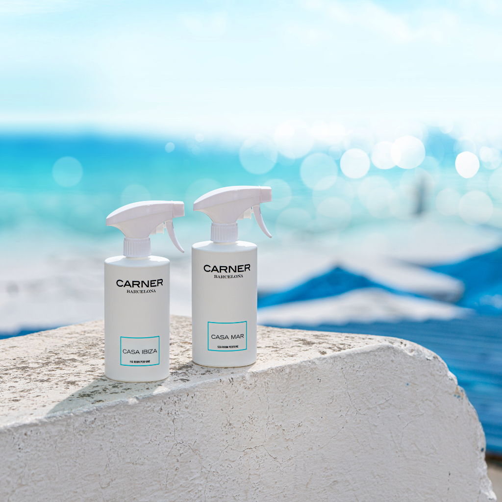 Two CASA MAR Sea Room Perfume bottles by GIFTS sit on a white stone surface with turquoise water and blue sky in the background, evoking a fresh Mediterranean coastal scent and atmosphere.