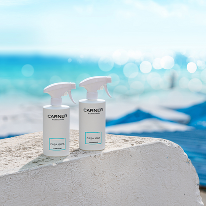 Two CASA MAR Sea Room Perfume bottles by GIFTS sit on a white stone surface with turquoise water and blue sky in the background, evoking a fresh Mediterranean coastal scent and atmosphere.