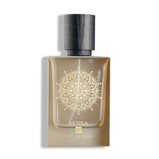 A rectangular SENNA Eau de Parfum bottle by Eau De Moe features a black cap, an ornate gold mandala design, and sweet powdery notes.