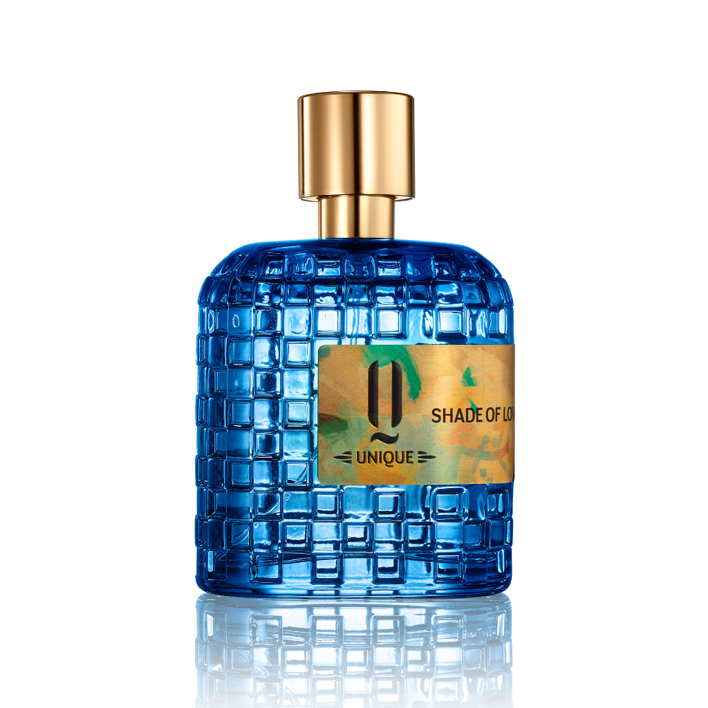 A blue textured glass perfume bottle with a gold cap and label reading "Shade of Love EDP - Jardin De Parfums" by Jardin De Parfums, on a white background, evoking patchouli vanilla fragrance with warm woody notes.