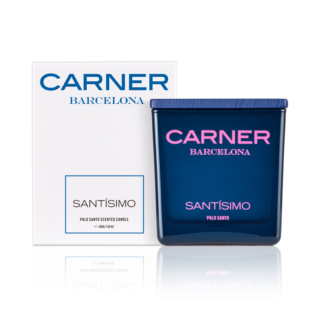 A blue glass SANTÍSIMO CANDLE by Carner, infused with musk, sits beside a white box featuring the Carner brand with blue and black text showing the scent name.