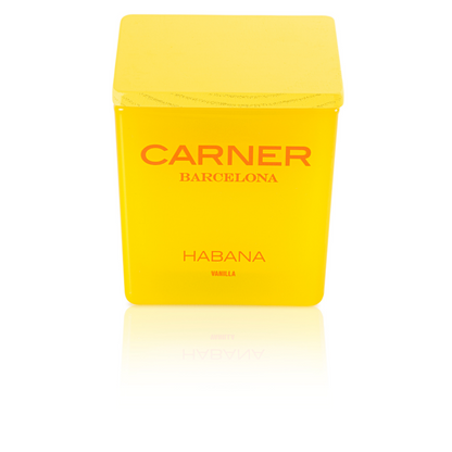 A bright yellow HABANA CANDLE by Carner Barcelona (GIFTS) with a matching square lid and bold red branding sits on a white surface, its label reading "CARNER BARCELONA" and "HABANA VANILLA.