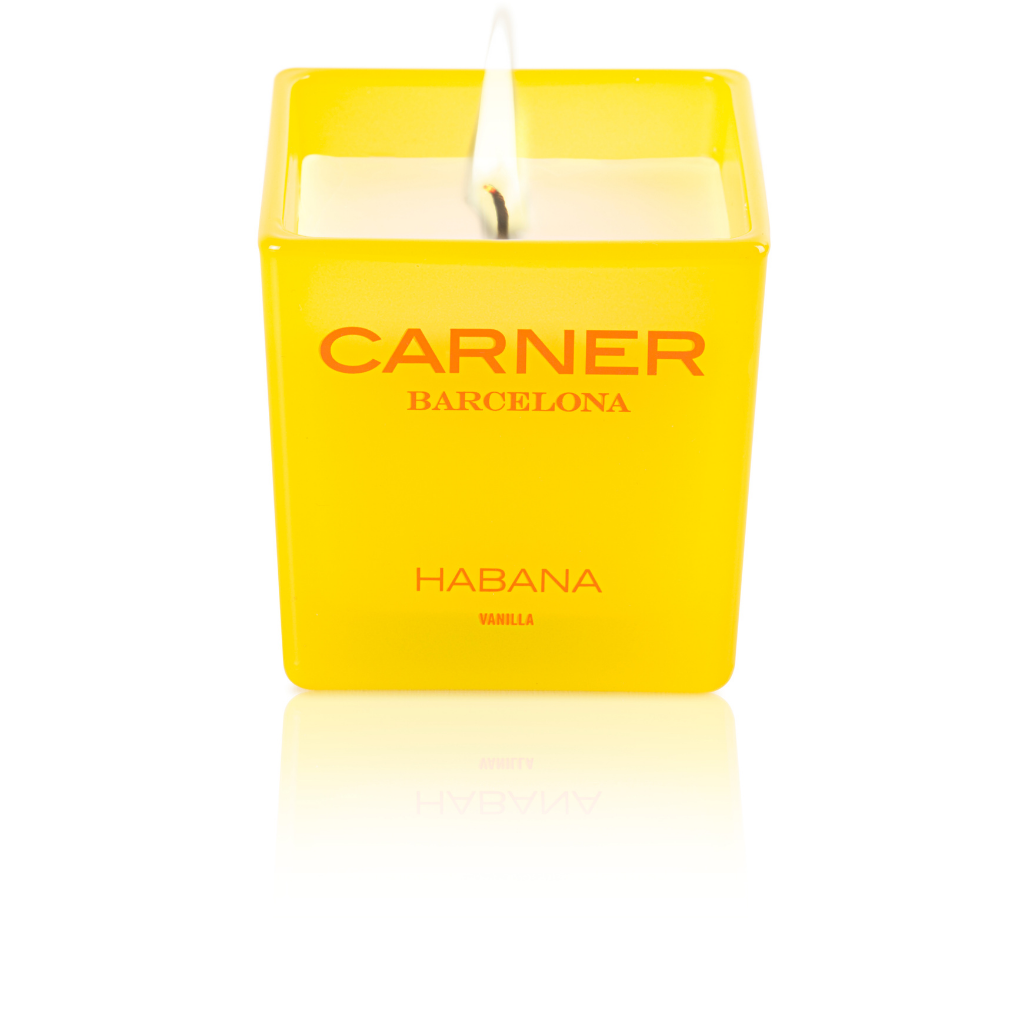 A lit HABANA CANDLE by GIFTS (Carner Barcelona) with a yellow square design flickers brightly against a white background.