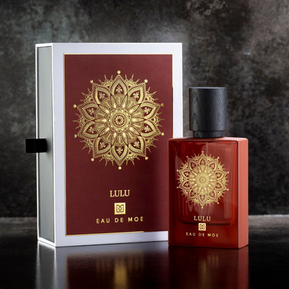 An 80ML red bottle of LULU Eau de Parfum by Eau De Moe, featuring a gold mandala and black cap, stands next to its matching box against a dark textured background.