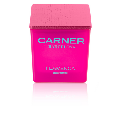 A vibrant pink FLAMENCA CANDLE by GIFTS, featuring a matching pink wooden lid and blue text labeled Orange Blossom and bergamot, rests on a white background—an eye-catching accent for any candle collection.