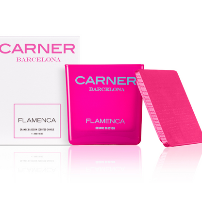 A vibrant pink FLAMENCA CANDLE by Carner Barcelona from GIFTS sits beside its white box with pink text; the candle’s pink lid leans against it.