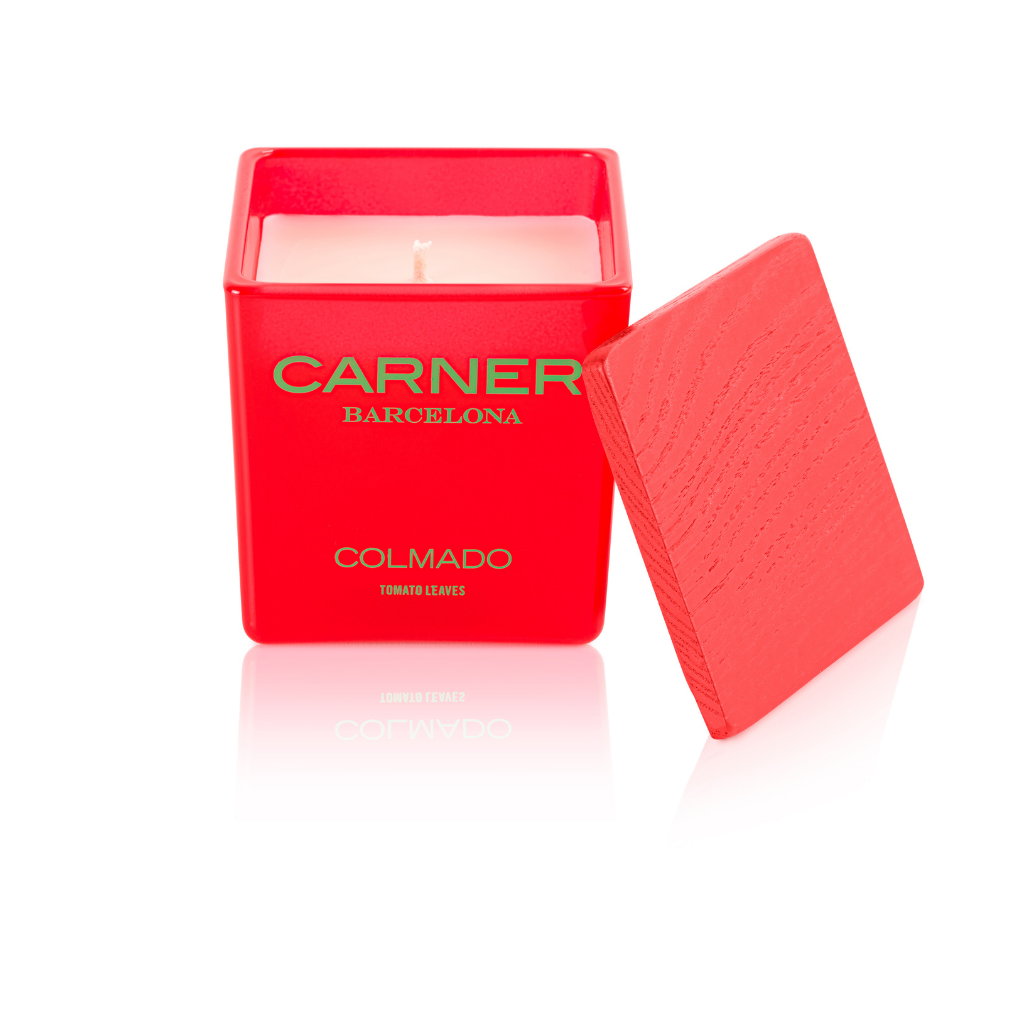 A vibrant red COLMADO CANDLE by GIFTS (Carner Barcelona), featuring "Tomato Leaves" on the front, is displayed with its matching textured lid on a glossy white surface.