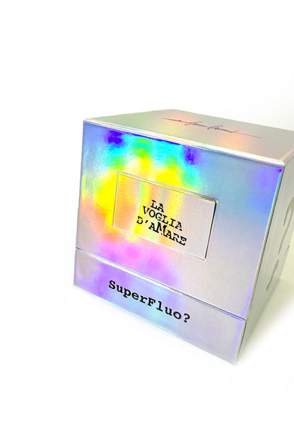 A holographic, iridescent box reading "LA VOGLIA D’AMARE" and "SuperFluo?" showcases Filippo Sorcinelli’s "The Desire To Love" Eau de Parfum, evoking a summer night fragrance against a plain white background.