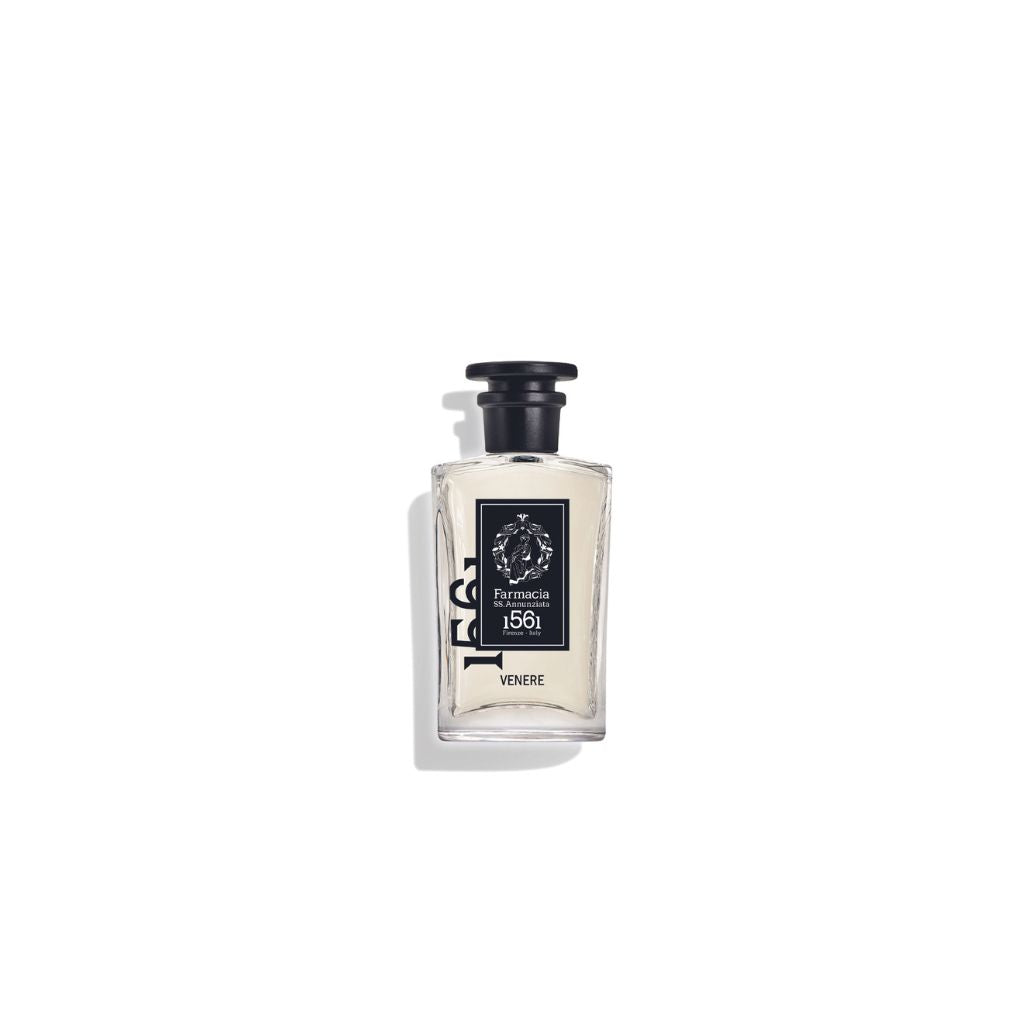 A clear glass bottle with a black cap and label displays Farmacia SS. Annunziata 1561 Venere Eau de Parfum, centered on white, evoking amber and musk notes.