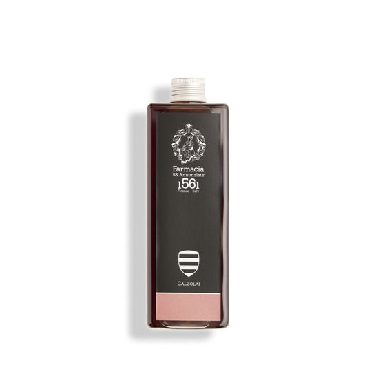 A rectangular bottle with a black label, white crest, and text reads "Farmacia SS. Annunziata 1561 Firenze - Italy." The Calzolai REFILL offers a luxurious leather-inspired home fragrance from Farmacia SS. Annunziata 1561.
