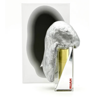The RUAH "breath" Eau de Parfum by Filippo Sorcinelli features a metallic, sculpted cap and angular bottle. It comes in front of a white box with a dark oval, offering creative spirit and sea breeze notes.