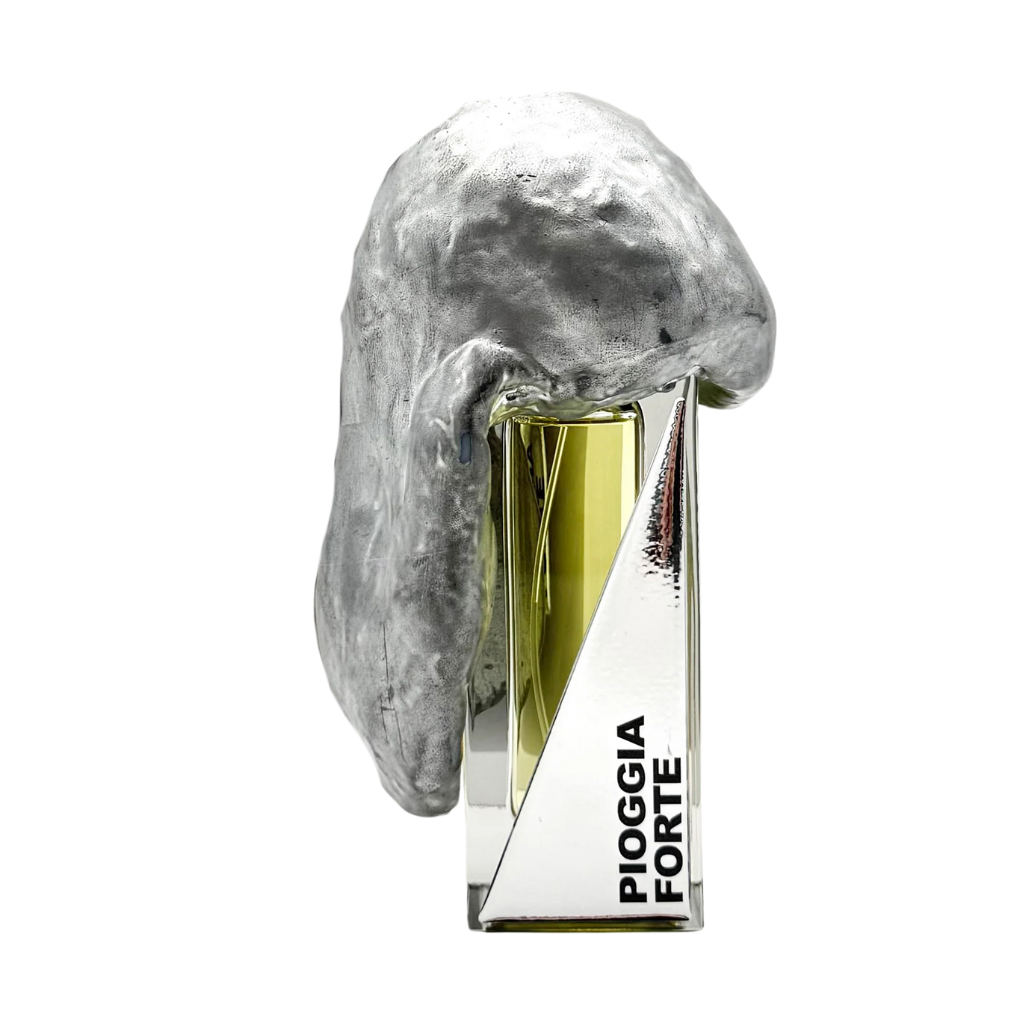 The PIOGGIA FORTE "heavy rain" Eau de Parfum by Filippo Sorcinelli features a silver metallic abstract sculpture draped across the bottle, with glimpses of glass and mirrored surfaces reflecting the fragrance’s artistry.