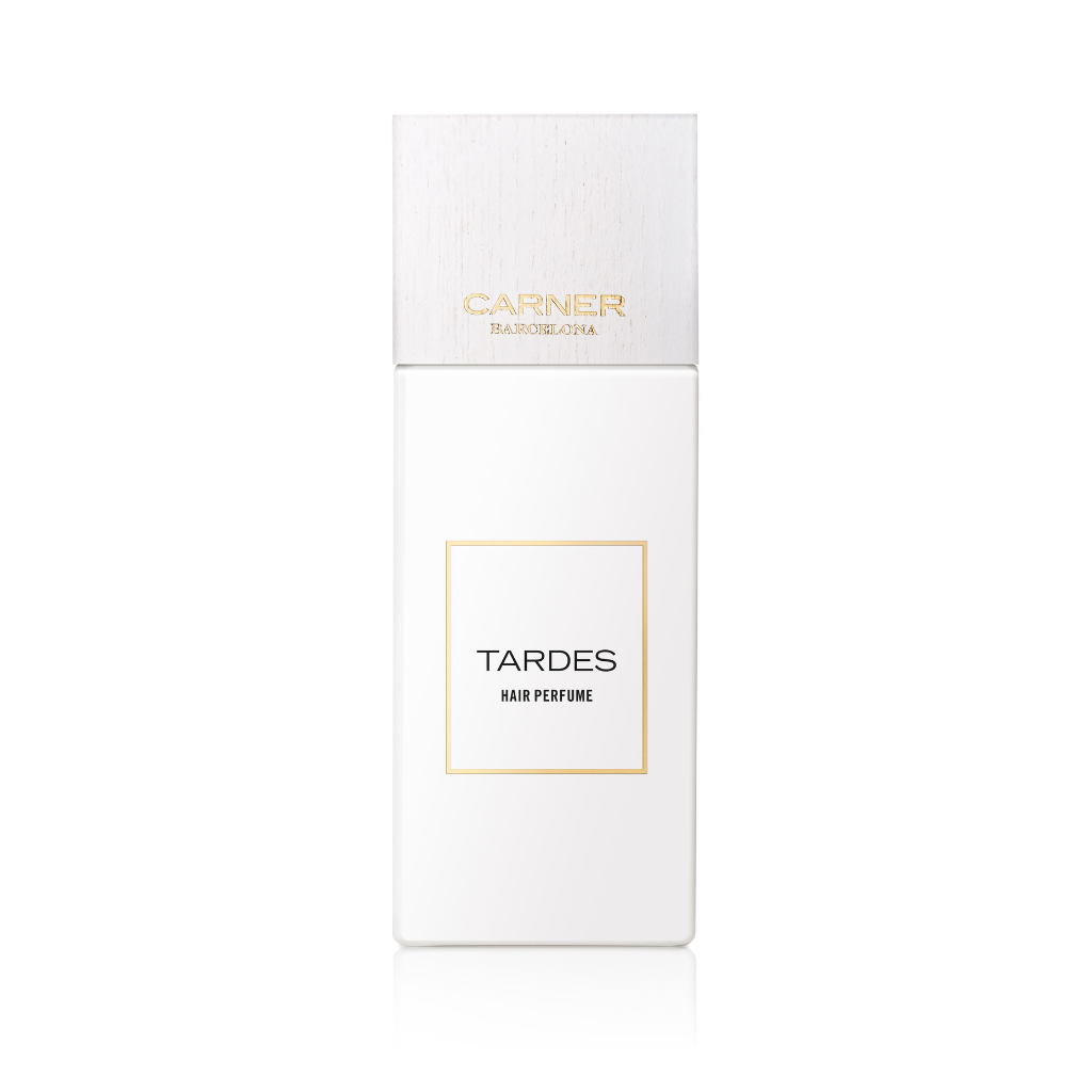 A white rectangular bottle of Carner TARDES HAIR PERFUME, with gold accents and a white cap, is shown on a plain background; this floral hair mist by Carner Barcelona offers a long-lasting scent.
