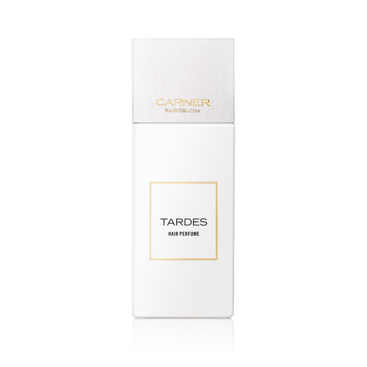 A white rectangular bottle of Carner TARDES HAIR PERFUME, with gold accents and a white cap, is shown on a plain background; this floral hair mist by Carner Barcelona offers a long-lasting scent.