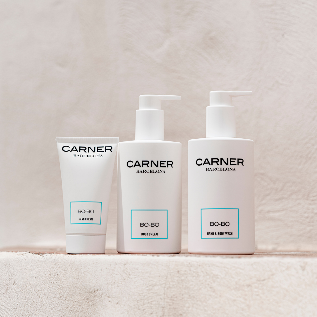 Three white GIFTS BO-BO Body Creams stand side by side on a light beige textured surface, each labeled “BO-BO” and infused with a fresh Mediterranean scent.