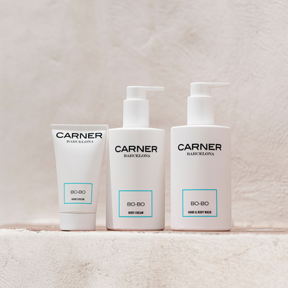 Three white GIFTS BO-BO Body Creams stand side by side on a light beige textured surface, each labeled “BO-BO” and infused with a fresh Mediterranean scent.