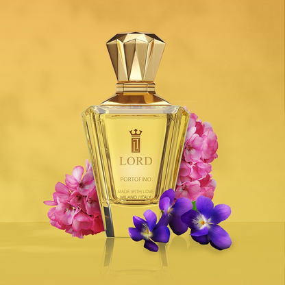 A gold-capped PORTOFINO Eau de Parfum by LORD MILANO stands against a yellow background, with pink and purple flowers evoking the Taif rose scent from the DREAM LIBRARY Collection.