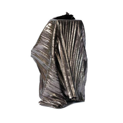A sculptural, metallic object with sharp ridges stands against white, capturing the drama and elegance of Filippo Sorcinelli’s UNUM _QUANDO_RAPITA_IN_ESTASI_ “when wrapped in ecstasy” EDP.
