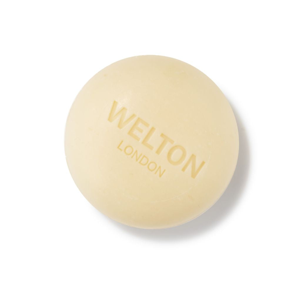 The EDEN DELUXE PERFUMED SOAP WITH SWEET ALMOND by Welton London is a round, pale beige soap bar engraved with the brand name, made in France and perfect for sensitive skin. Shown against a white background.