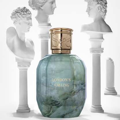The gold-capped LONDON'S CALLING Eau de Parfum by Sense of Scent, in a marble-patterned bottle, stands before classical white busts and evokes an elegant, artistic ambiance with its exotic Last Orient-inspired fragrance.
