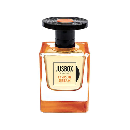 A square glass bottle of Jusbox 14 Hour Dream Eau de Parfum holds amber liquid, features a black round cap with an orange accent, and offers Antoine Lie’s signature oriental notes with a rich patchouli scent.