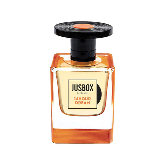 A square glass bottle of Jusbox 14 Hour Dream Eau de Parfum holds amber liquid, features a black round cap with an orange accent, and offers Antoine Lie’s signature oriental notes with a rich patchouli scent.