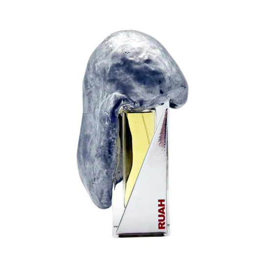 RUAH "breath" Eau de Parfum by Filippo Sorcinelli features a shiny silver abstract cap over yellow liquid, with bold red RUAH text on the front. This creative scent bottle is set against a white background.