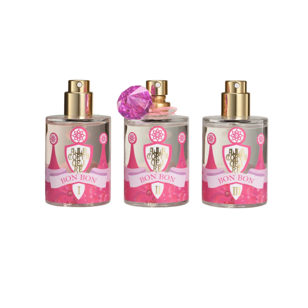 Three BON BON - Nobile 1942 perfumes by Nobile 1942, with gold spray tops and pink labels, are displayed on a white background. The center bottle features a pink gemstone cap. This sweet scent evokes candied sugar and fairy tale dreams.