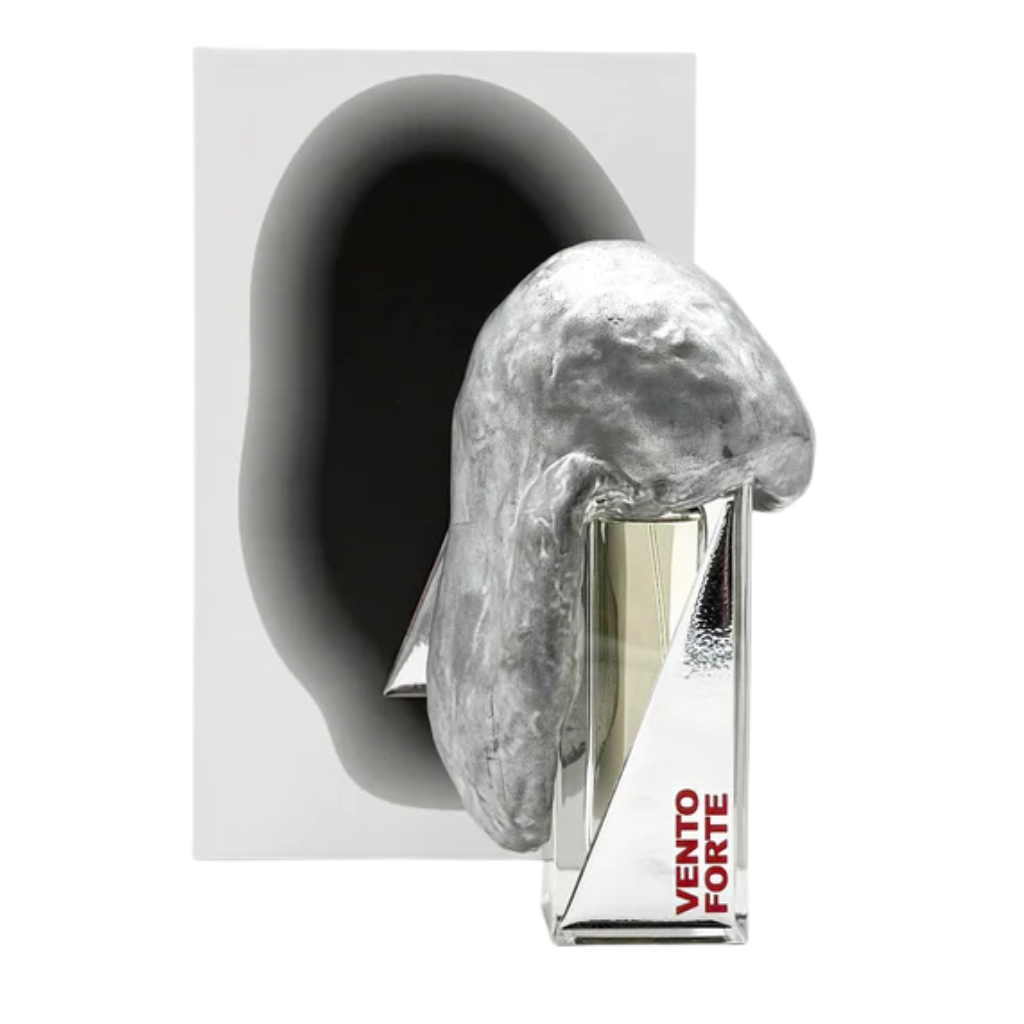 The VENTO FORTE "strong wind" Eau de Parfum by Filippo Sorcinelli features a distinctive bottle with a shiny, irregular silver cap and sits before a white box adorned with an abstract dark oval—echoing themes of Exodus and divine intervention.