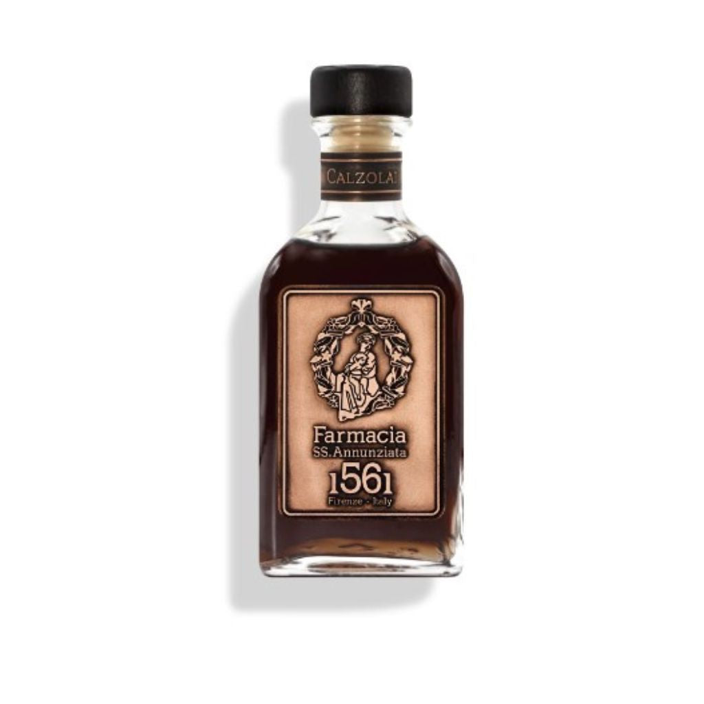 A small glass bottle with dark liquid, a black cap, and a beige label reading Farmacia SS. Annunziata 1561—Calzolai DIFFUSER, a luxurious leather home fragrance by Farmacia SS. Annunziata 1561.