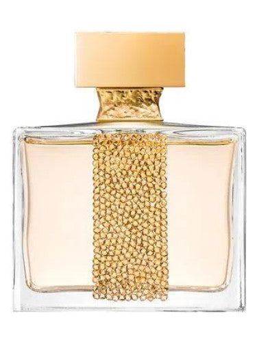 The ROYAL MUSKA Eau de Parfum by M.Micallef comes in a transparent rectangular bottle with a gold cap and a vertical strip of gold beads, holding light amber liquid that exudes an elegant white musk and tropical scent.