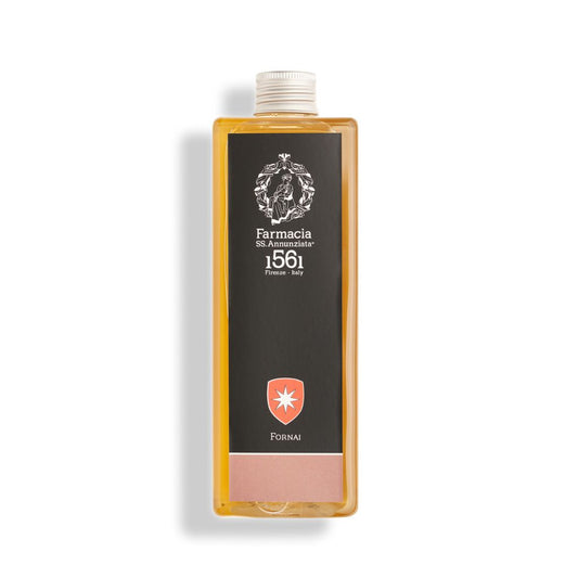 A rectangular clear bottle of Fornai REFILL - Farmacia by Farmacia SS. Annunziata 1561 holds golden liquid, with a black label showing the brand name and adorned by a white emblem plus a red shield with a white star.