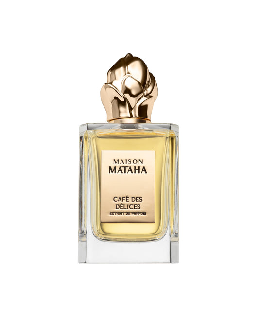 A clear glass bottle with a gold sculpted rose cap holds Café des Délices Extrait de Parfum by Maison Mataha, its light amber liquid suggesting a coffee scent. The bottle is set against a white background.