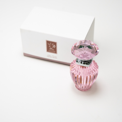 The Hind Al Oud Pink Oud Concentrated Oil 6ml features a pink faceted glass bottle with a jeweled cap, displayed before a white box with brown and white labeling—suggesting notes of jasmine and cashmere wood.