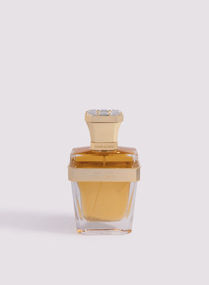 A clear glass bottle with a gold cap and band, filled with amber-hued Oud Zayed Parfum by Hind Al Oud, an exquisite Emirati fragrance, showcased against a light pale background.